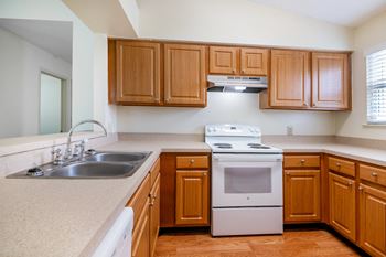 A kitchen with wooden cabinets and a white stove top oven
